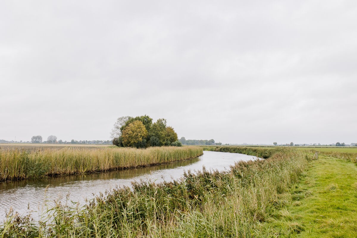 De Oude Lauwers maakt een bocht door groen vlak landschap.